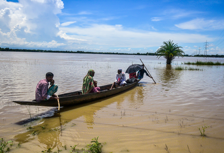 Family traveling by boat through floodwater in Assam